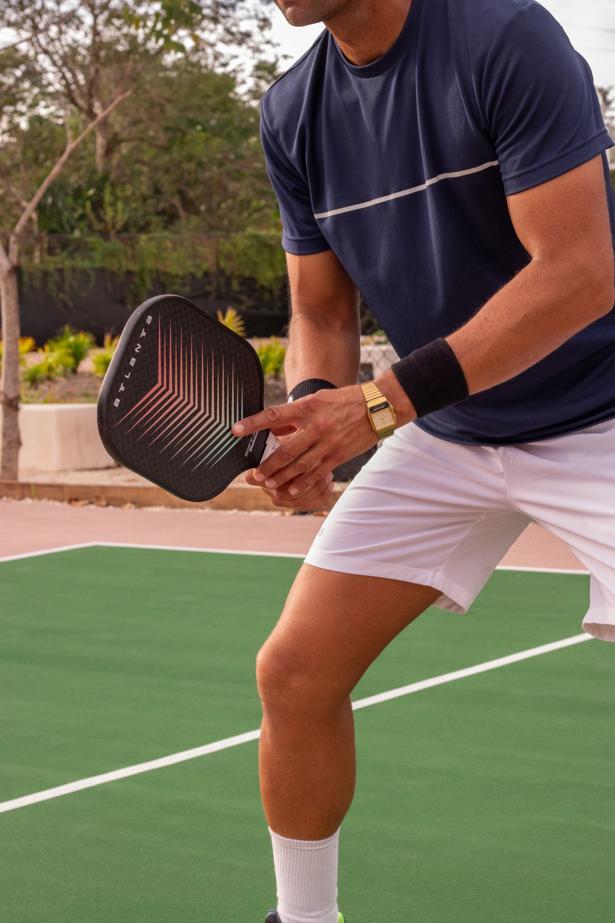 A pickleball player in a blue shirt holding a paddle, ready for the next shot.