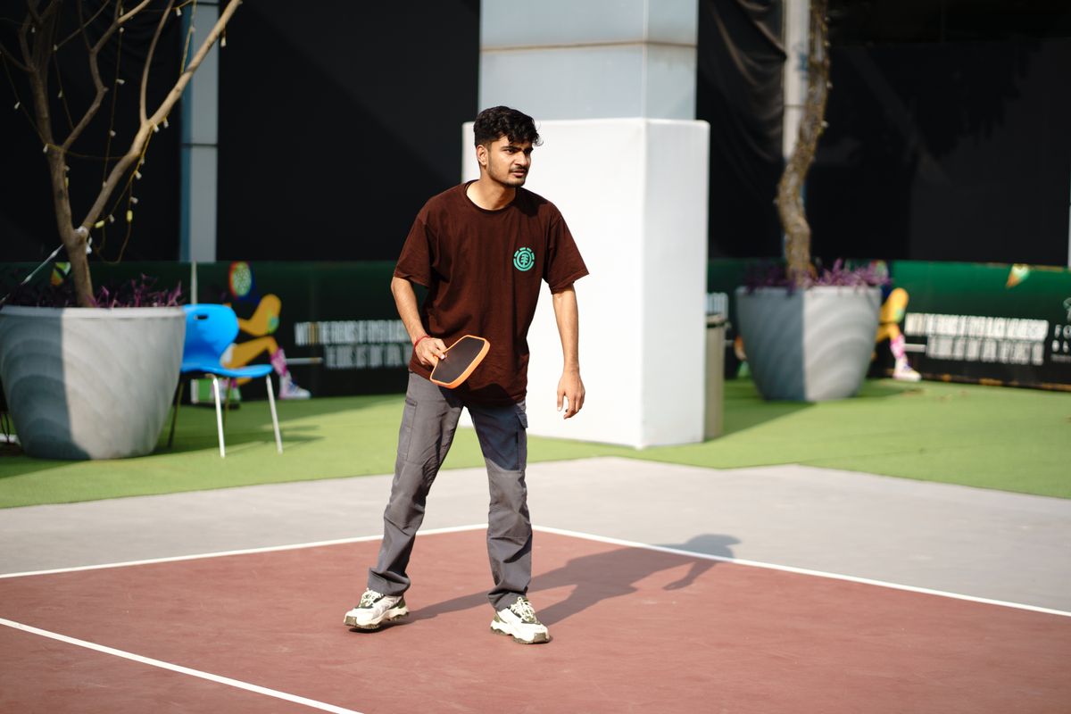 A player watching the ball with a pickleball paddle in hand on a sunny court.