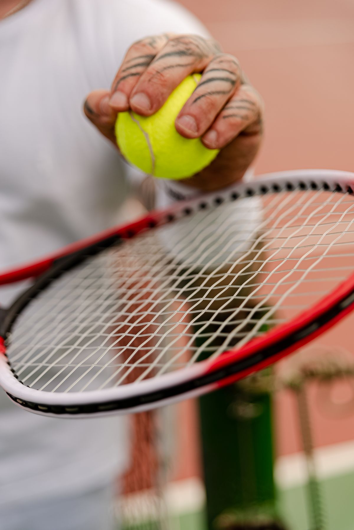 A player’s point of view, holding a yellow tennis ball above their racket.